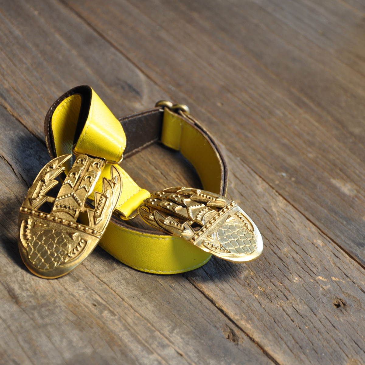Yellow leather Twice Hook Belt by Peripherii on yellow leather placed on a wooden surface