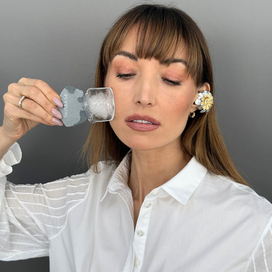 Woman using Glissage, a no oil guasha, to massage her face.