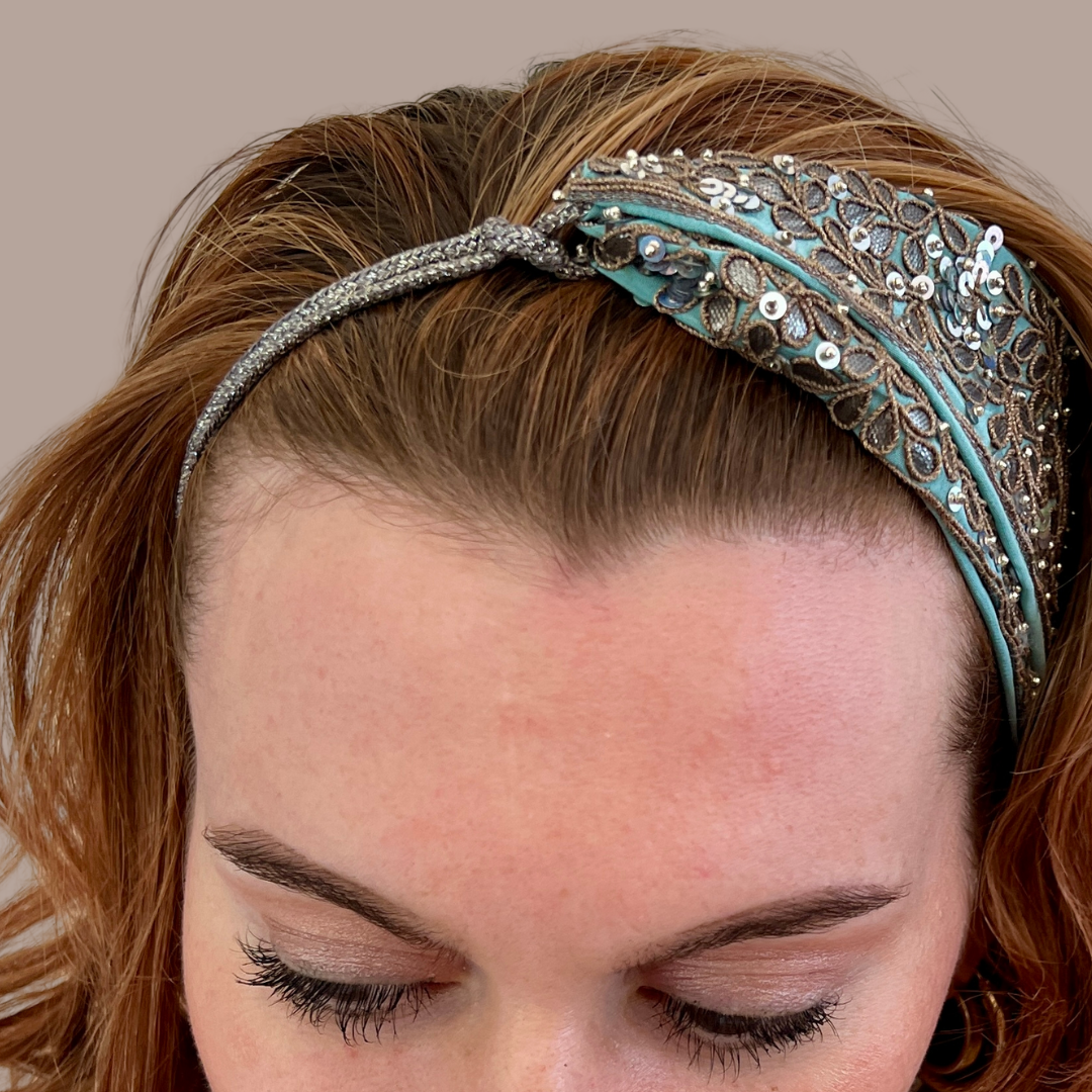 Woman wearing aqua asymmetrical headband with metallic appliqués, sequins and silver cord