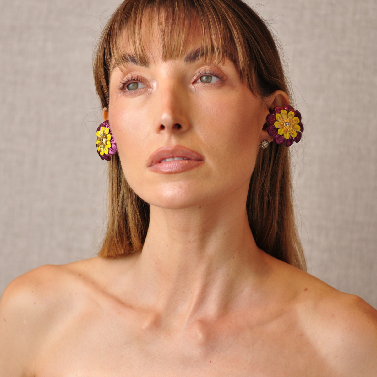 PERIPHERII PRIAMBLE Gita Bluetooth earbuds, close-up of burgundy, yellow and gold petals with a crystal center.