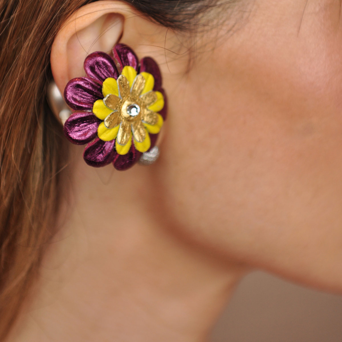 PERIPHERII PRIAMBLE Gita Bluetooth earbuds, close-up of burgundy, yellow and gold petals with a crystal center.