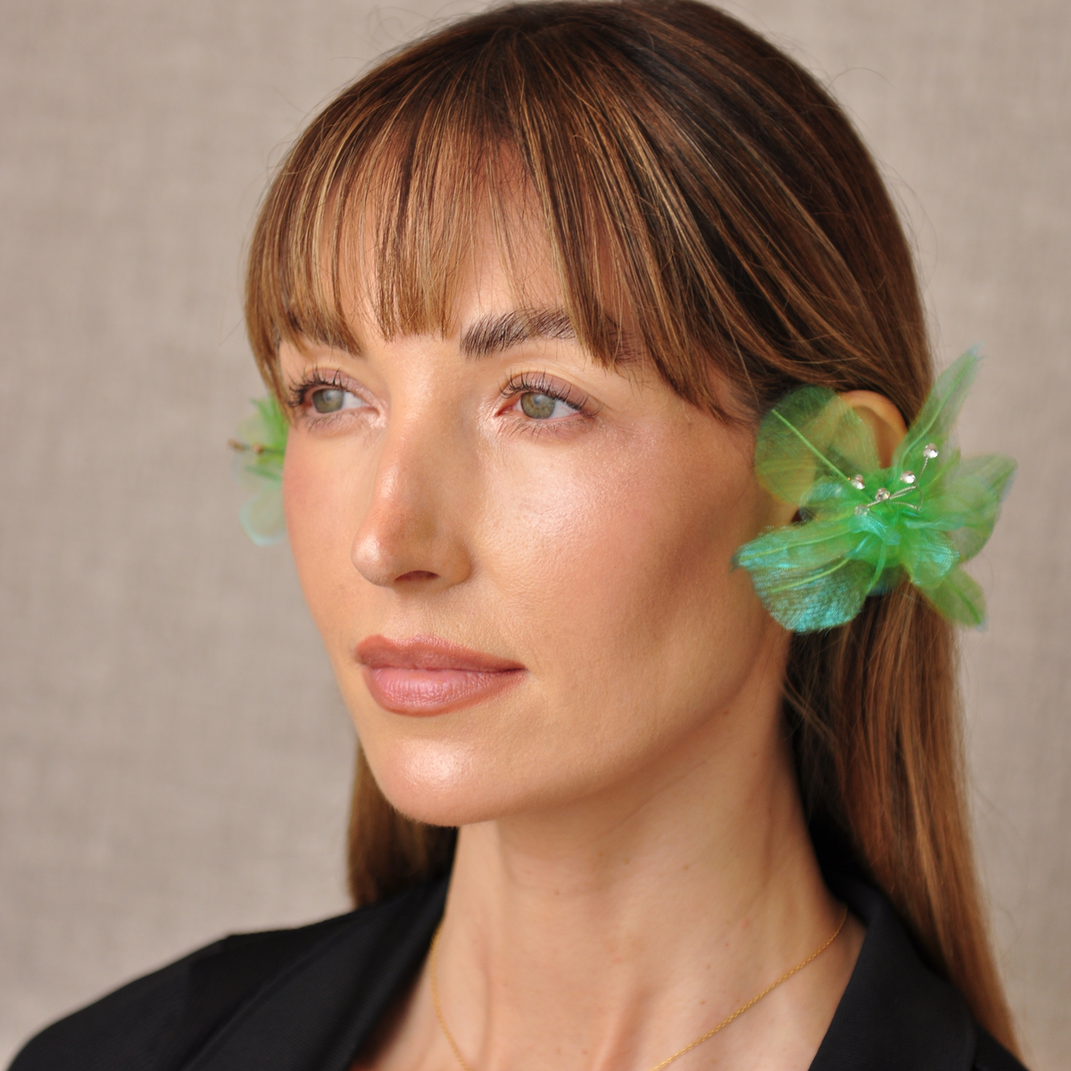 Three-quarter view of a model wearing green PRIAMBLE Sonnet audio earrings, showing the layered floral design.