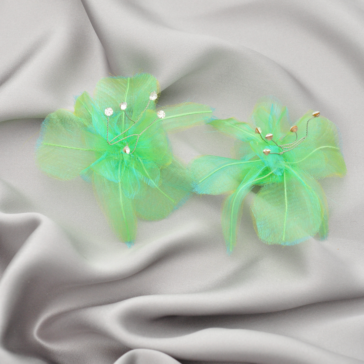 Pair of green Priamble Sonnet floral audio earrings with translucent petals and crystal accents on gray silk charmeuse fabric.