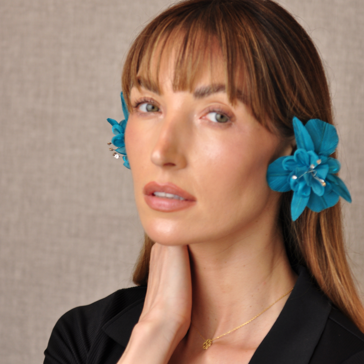 Three-quarter portrait of a model wearing teal PRIAMBLE Sonnet floral orchid audio earrings.