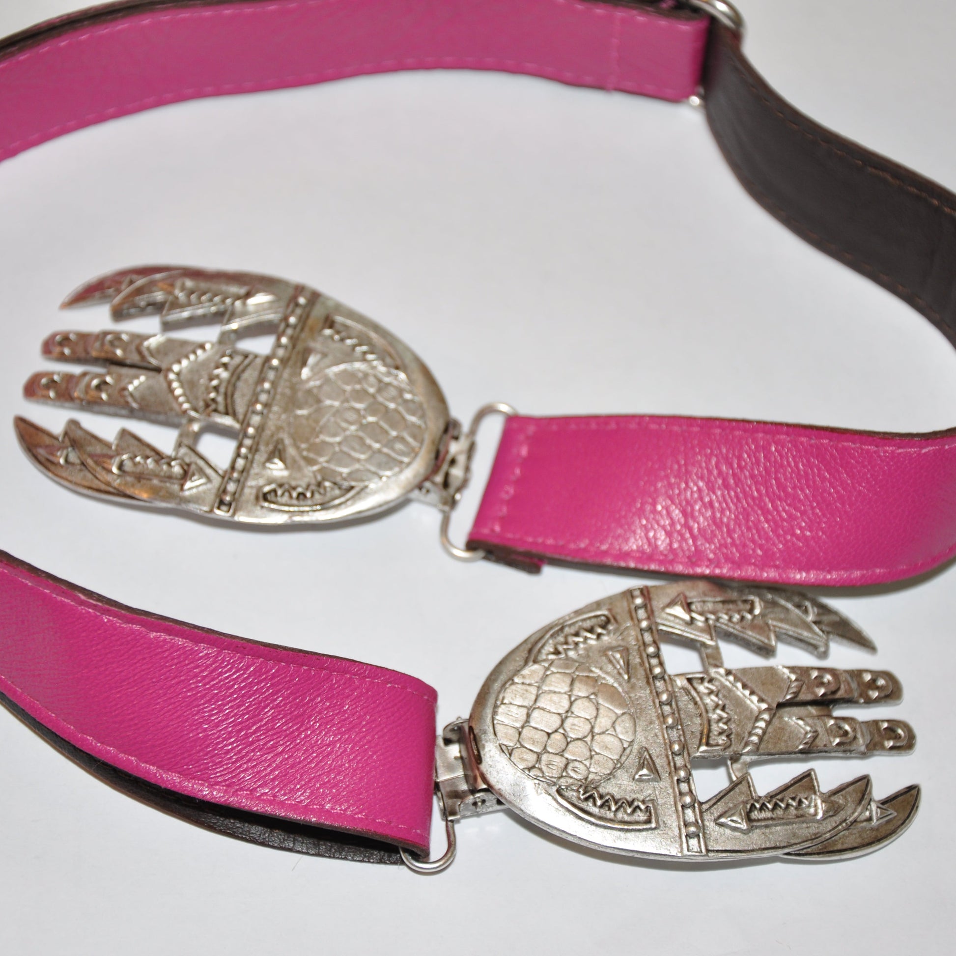 Fuchsia Pink Twice Hook Buckle-less belt with silver hand-shaped buckles on a white background